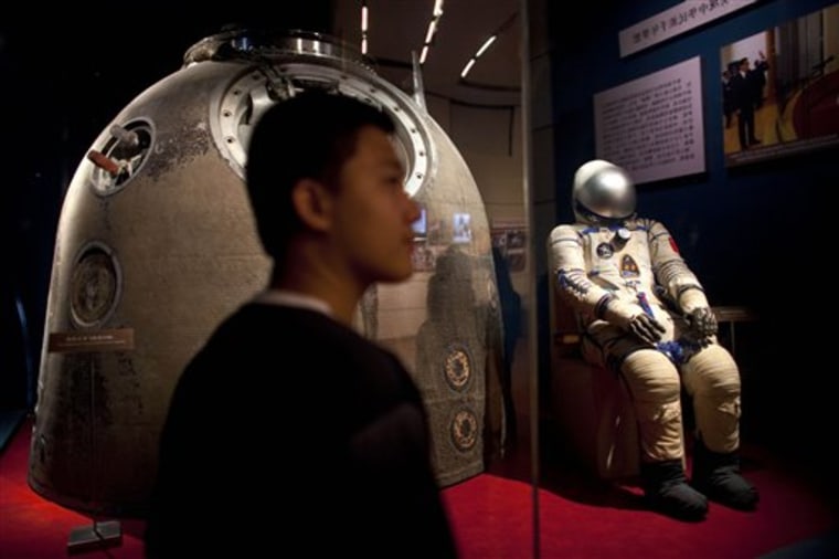 A visitor to a Beijing exhibition stands near the Shenzhou 5 re-entry capsule that was used in China's first human spaceflight mission,as well as the spacesuit worn by crew member Yang Liwei. Some experts worry the U.S. could slip behind China in human spaceflight.